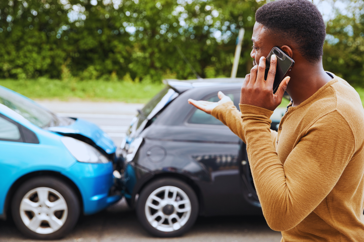 Pessoa falando ao celular após acidente de carro, representando sinistro no seguro auto.