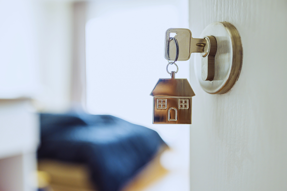 Seguro para casa alugada representado por chaveiro em formato de casa na porta.